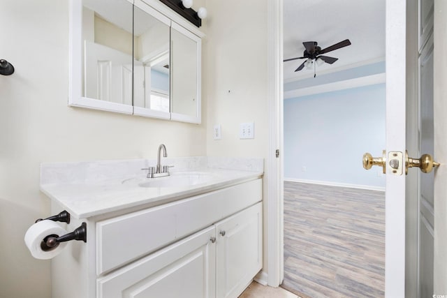 bathroom featuring ornamental molding, ceiling fan, vanity, wood finished floors, and baseboards