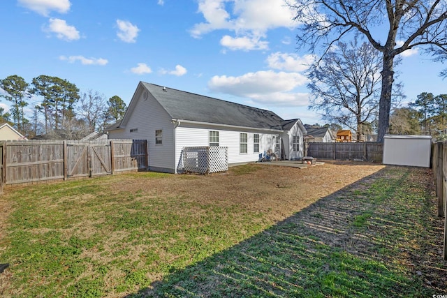 back of property with a storage shed, a fenced backyard, an outbuilding, a gate, and a yard