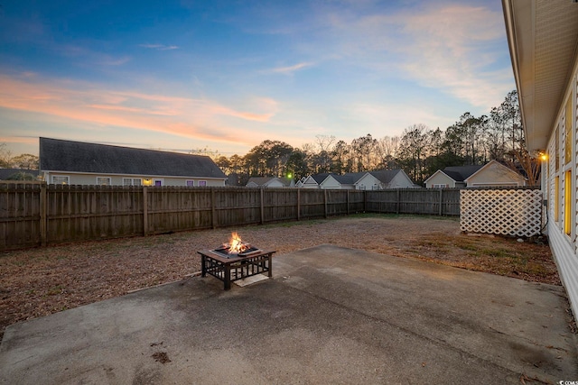 patio terrace at dusk featuring an outdoor fire pit and a fenced backyard