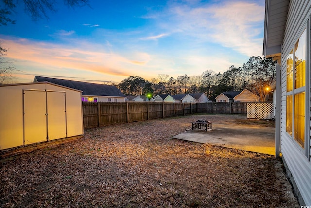 view of yard with a patio, an outdoor fire pit, a fenced backyard, a storage shed, and an outdoor structure