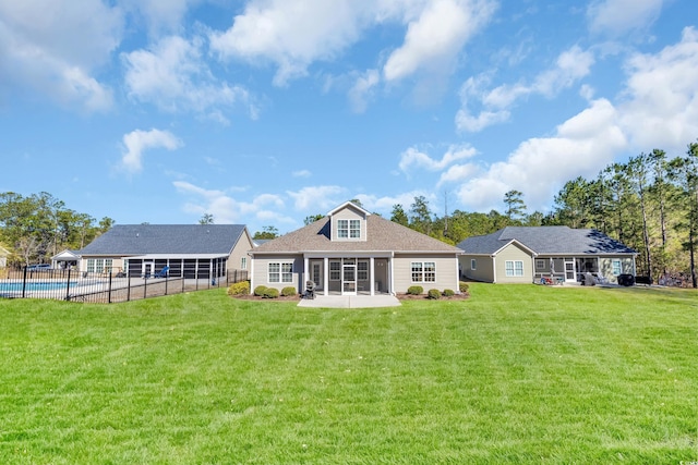 rear view of house featuring a fenced in pool, a sunroom, a yard, and a patio