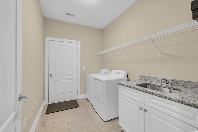 washroom featuring separate washer and dryer, a sink, visible vents, baseboards, and cabinet space