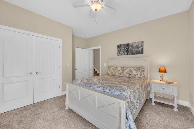 bedroom featuring light carpet, ceiling fan, baseboards, and a closet