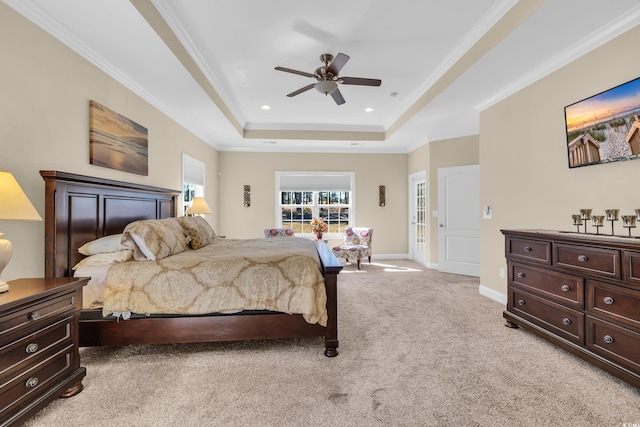 bedroom with light carpet, a ceiling fan, baseboards, ornamental molding, and a tray ceiling