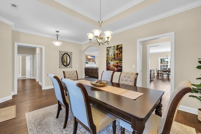 dining space with baseboards, crown molding, arched walkways, and dark wood-type flooring