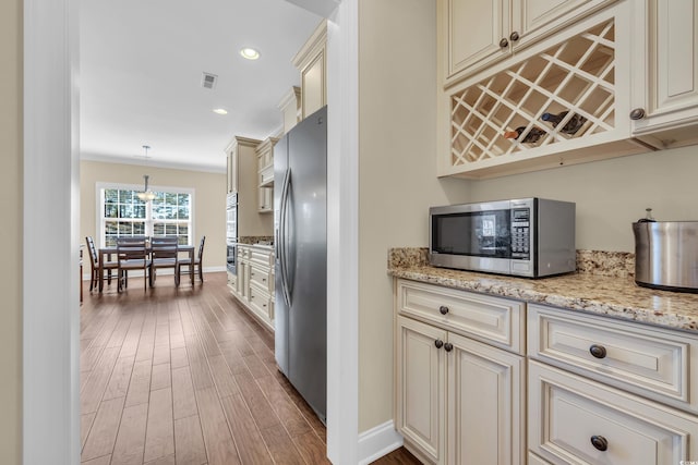 kitchen with visible vents, hanging light fixtures, cream cabinets, appliances with stainless steel finishes, and wood finished floors