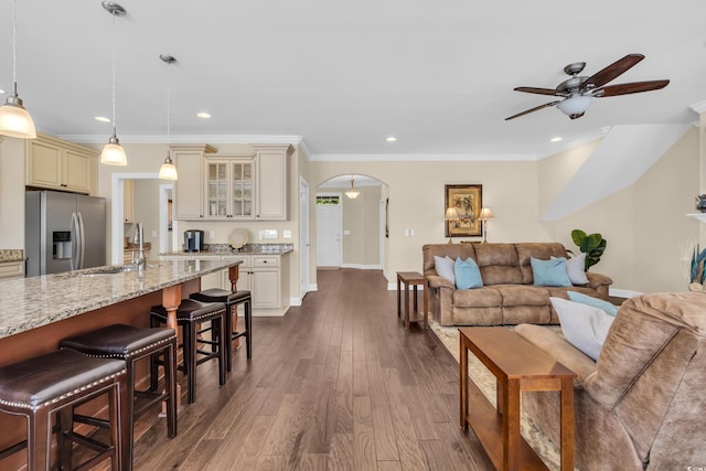 living room featuring dark wood-style floors, arched walkways, ornamental molding, and baseboards