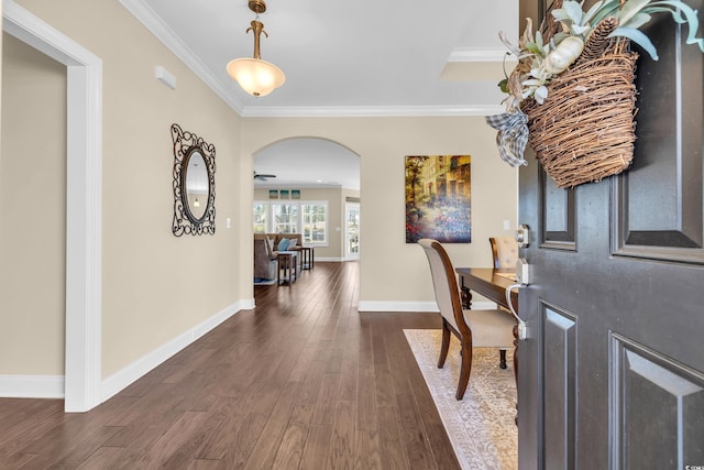 entryway with baseboards, arched walkways, dark wood-style flooring, and ornamental molding