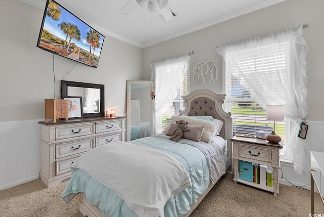 bedroom featuring ornamental molding, light colored carpet, wainscoting, and a ceiling fan