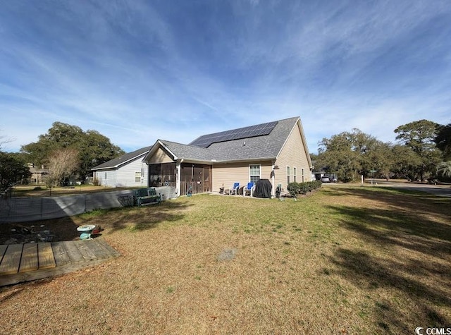 back of house featuring solar panels, a lawn, and a sunroom