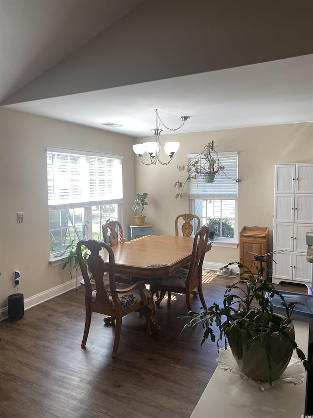 dining area featuring vaulted ceiling, a notable chandelier, dark wood finished floors, and baseboards