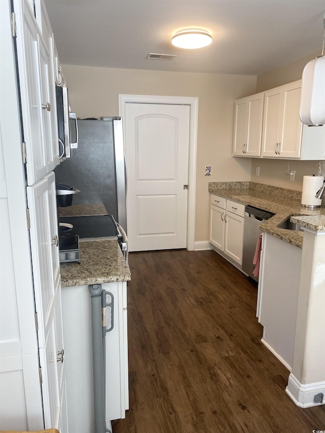 kitchen featuring pendant lighting, appliances with stainless steel finishes, dark wood-type flooring, white cabinetry, and a sink