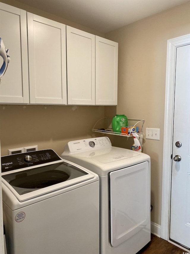 laundry area featuring dark wood-type flooring, washer and clothes dryer, and cabinet space