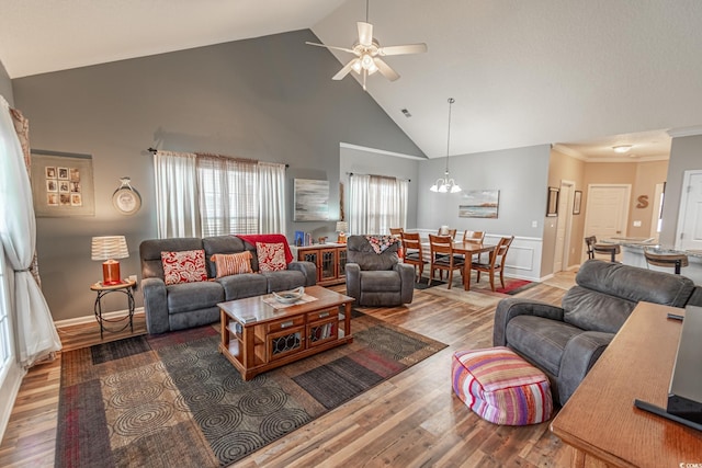 living area with high vaulted ceiling, a wainscoted wall, wood finished floors, a ceiling fan, and crown molding