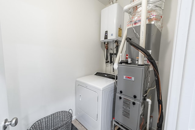 washroom with laundry area, water heater, and washer / clothes dryer