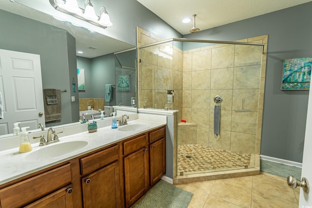 bathroom with double vanity, a stall shower, a sink, and tile patterned floors