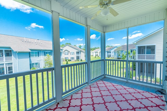 unfurnished sunroom with a residential view and a ceiling fan