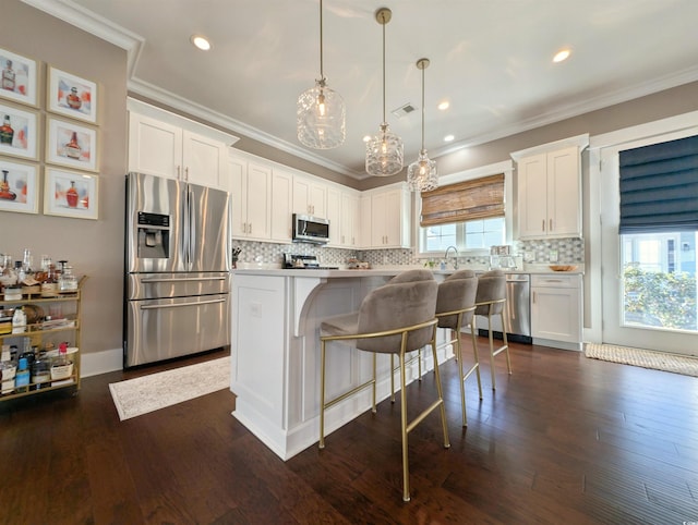 kitchen featuring stainless steel appliances, white cabinets, a kitchen island, and hanging light fixtures