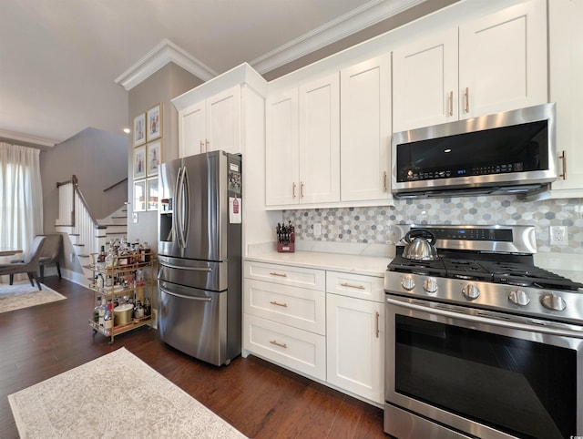 kitchen featuring stainless steel appliances, dark wood-style flooring, white cabinets, ornamental molding, and tasteful backsplash