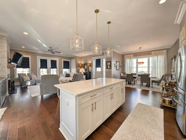 kitchen with light countertops, a center island, white cabinetry, and decorative light fixtures