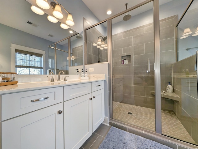 full bathroom with a stall shower, tile patterned flooring, visible vents, and vanity