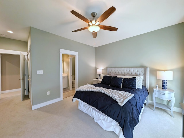 bedroom featuring light carpet, connected bathroom, baseboards, and ceiling fan