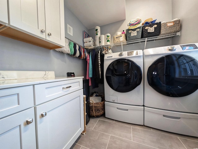 clothes washing area with visible vents, separate washer and dryer, light tile patterned flooring, and cabinet space