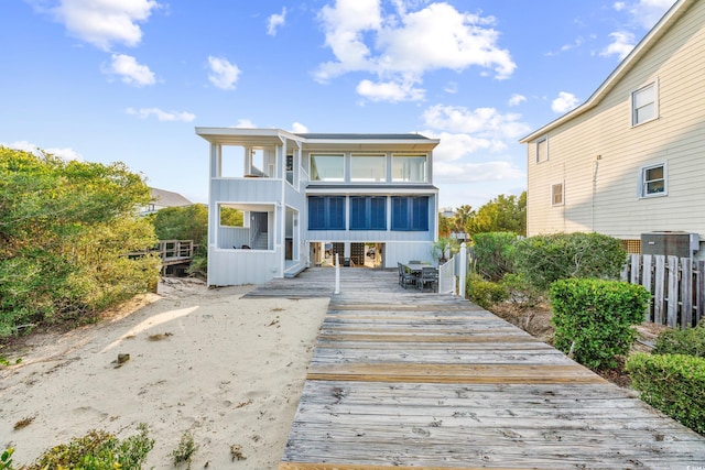 back of property featuring board and batten siding, a patio area, fence, and a balcony