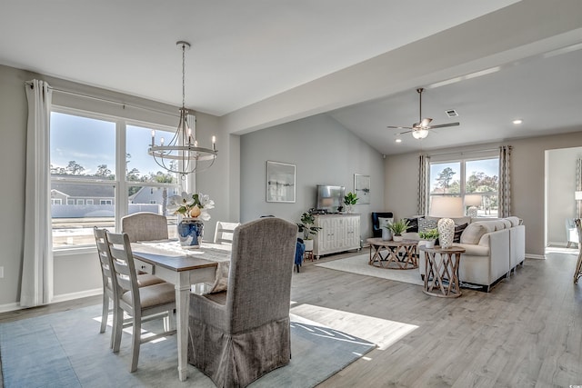 dining area with baseboards, ceiling fan with notable chandelier, wood finished floors, and lofted ceiling