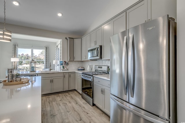 kitchen with gray cabinets, decorative backsplash, appliances with stainless steel finishes, a sink, and light countertops