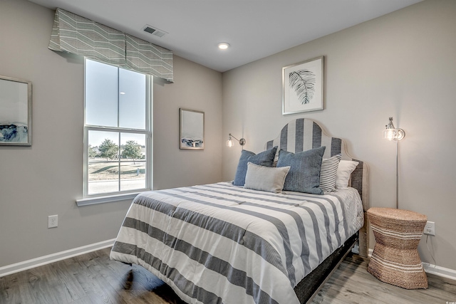 bedroom featuring baseboards, wood finished floors, and visible vents