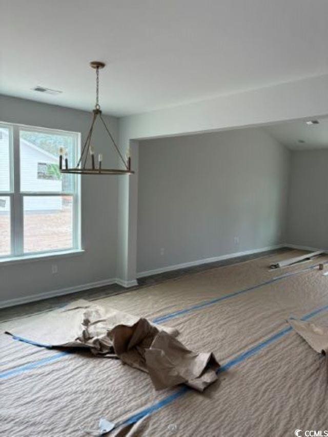 unfurnished dining area featuring a chandelier and baseboards