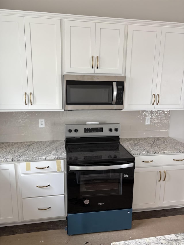 kitchen with electric range oven, stainless steel microwave, and white cabinets