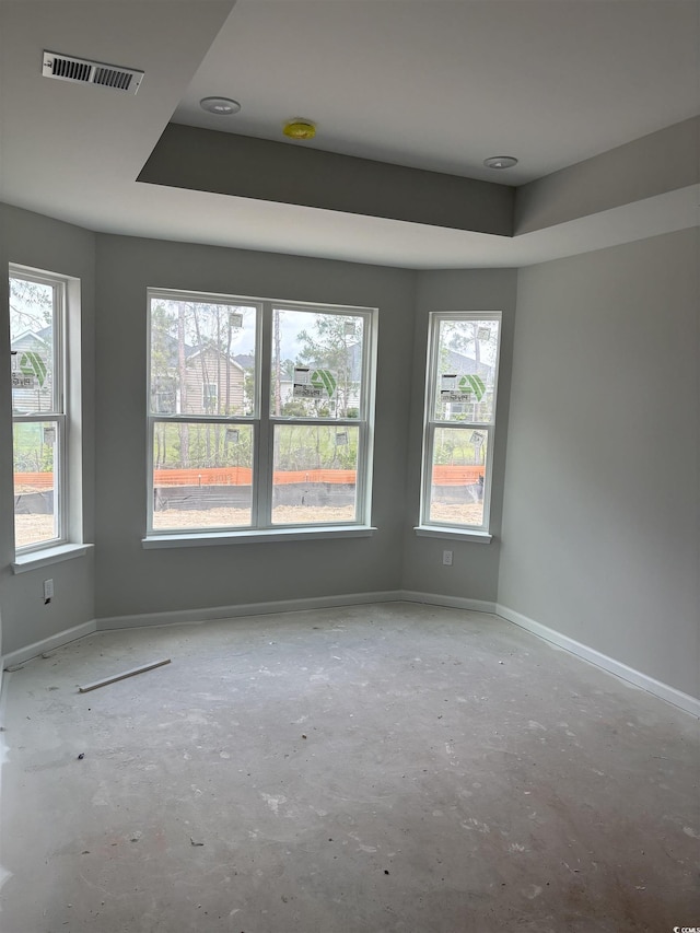 spare room with visible vents, a raised ceiling, and baseboards