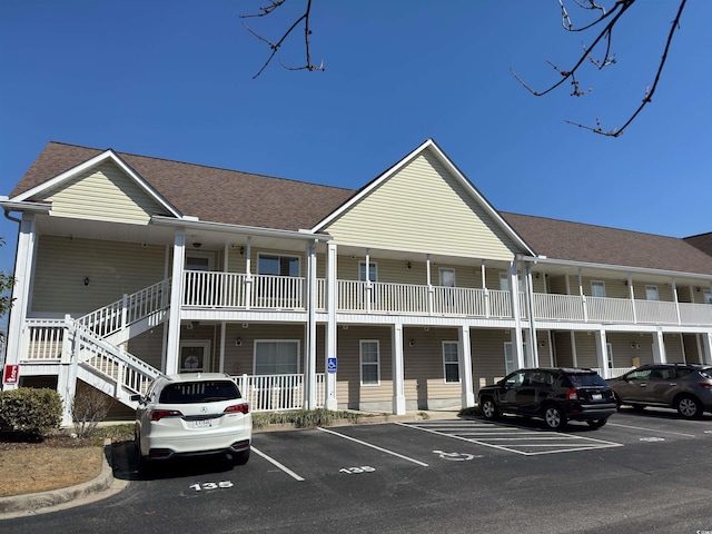 view of property with stairs and uncovered parking