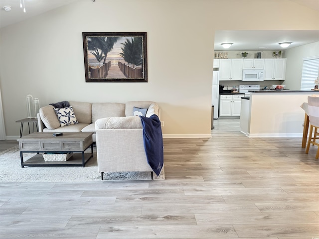 living area with light wood-style floors, baseboards, and vaulted ceiling