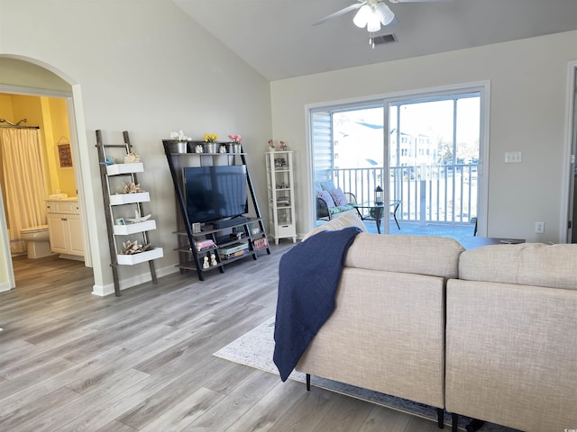 living area featuring arched walkways, visible vents, ceiling fan, wood finished floors, and vaulted ceiling