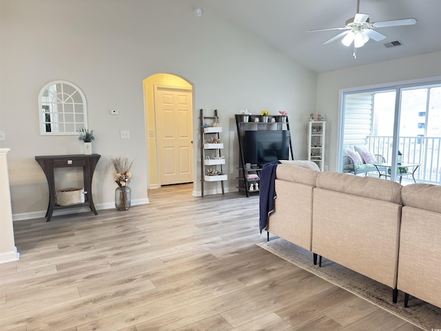 living room featuring lofted ceiling, light wood-style flooring, visible vents, baseboards, and a ceiling fan