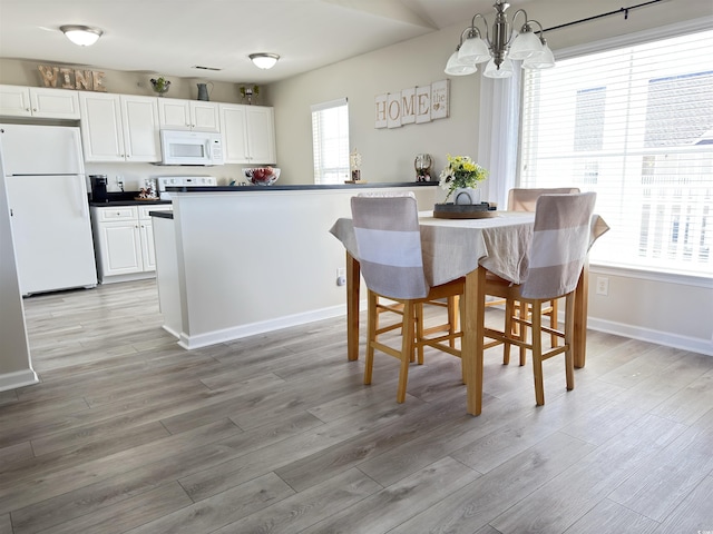 dining room featuring a chandelier, baseboards, and light wood finished floors