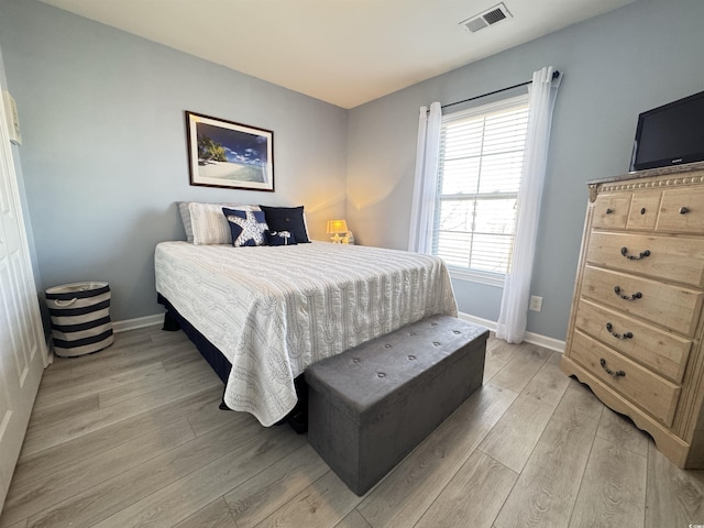 bedroom featuring baseboards, visible vents, and light wood finished floors