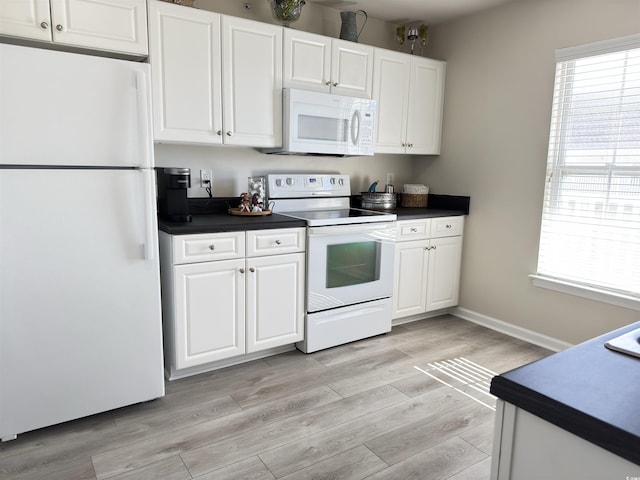 kitchen featuring dark countertops, white appliances, light wood-style flooring, and white cabinets