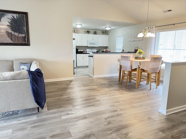 dining area featuring light wood-type flooring, vaulted ceiling, baseboards, and an inviting chandelier