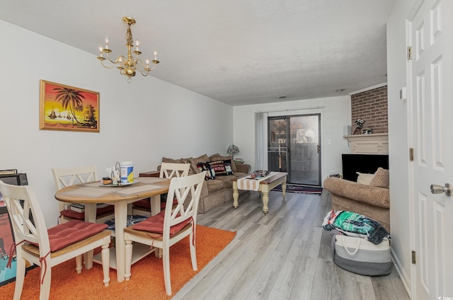 dining area featuring a large fireplace, light wood-style flooring, and an inviting chandelier