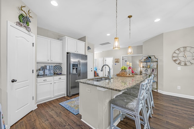 kitchen with light stone countertops, dark wood-type flooring, a sink, and stainless steel fridge with ice dispenser