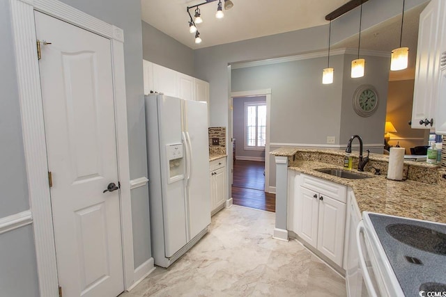 kitchen featuring white refrigerator with ice dispenser, light stone counters, white cabinetry, pendant lighting, and a sink