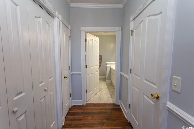 hallway featuring dark wood finished floors, crown molding, and baseboards