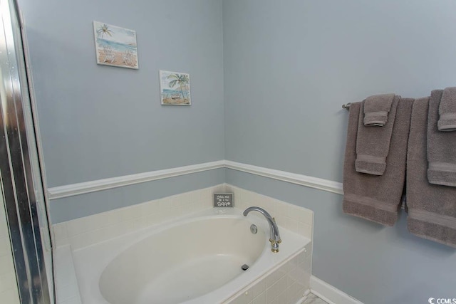 bathroom with baseboards and a bath