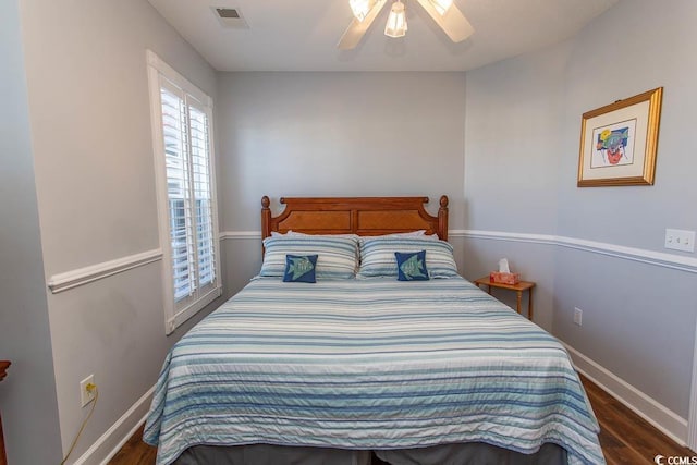 bedroom featuring a ceiling fan, visible vents, baseboards, and wood finished floors