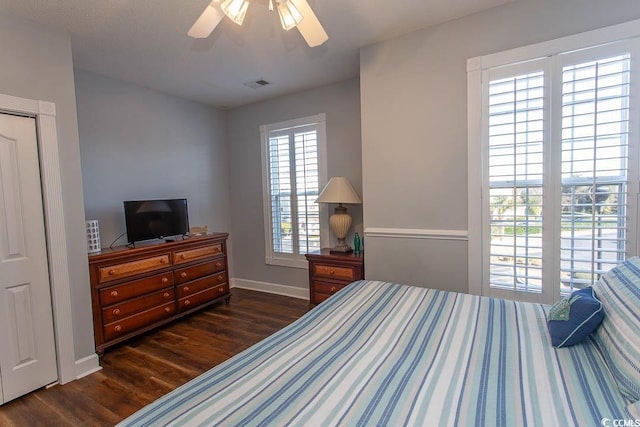 bedroom featuring a ceiling fan, visible vents, dark wood finished floors, and baseboards