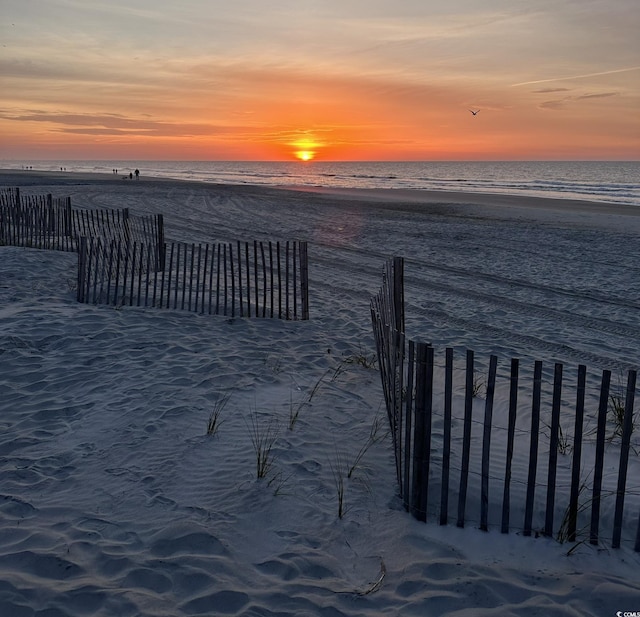 view of home's community with a view of the beach, a water view, and fence